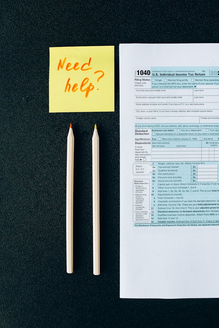 A tax form 1040 with a Need help? sticky note and pencils on a black surface.